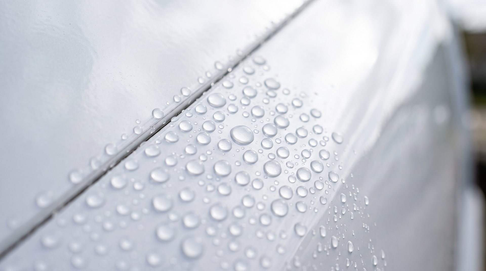 Water beading into tight droplets on a ceramic coated white motorhome body panel